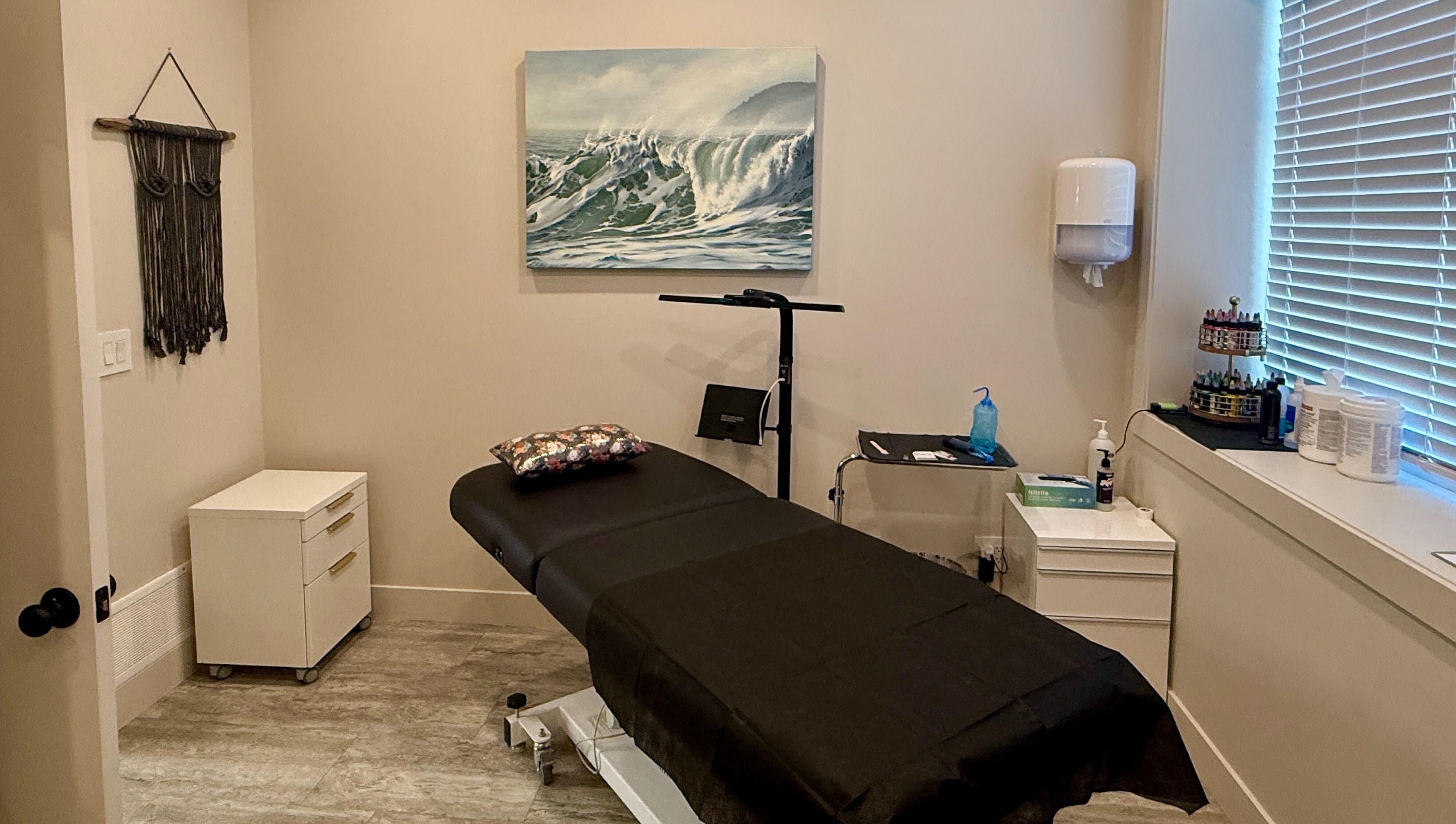 Calm treatment room at Jessie Grant - Ember Studio, Kelowna, British Columbia, CA with massage bed and ocean artwork.