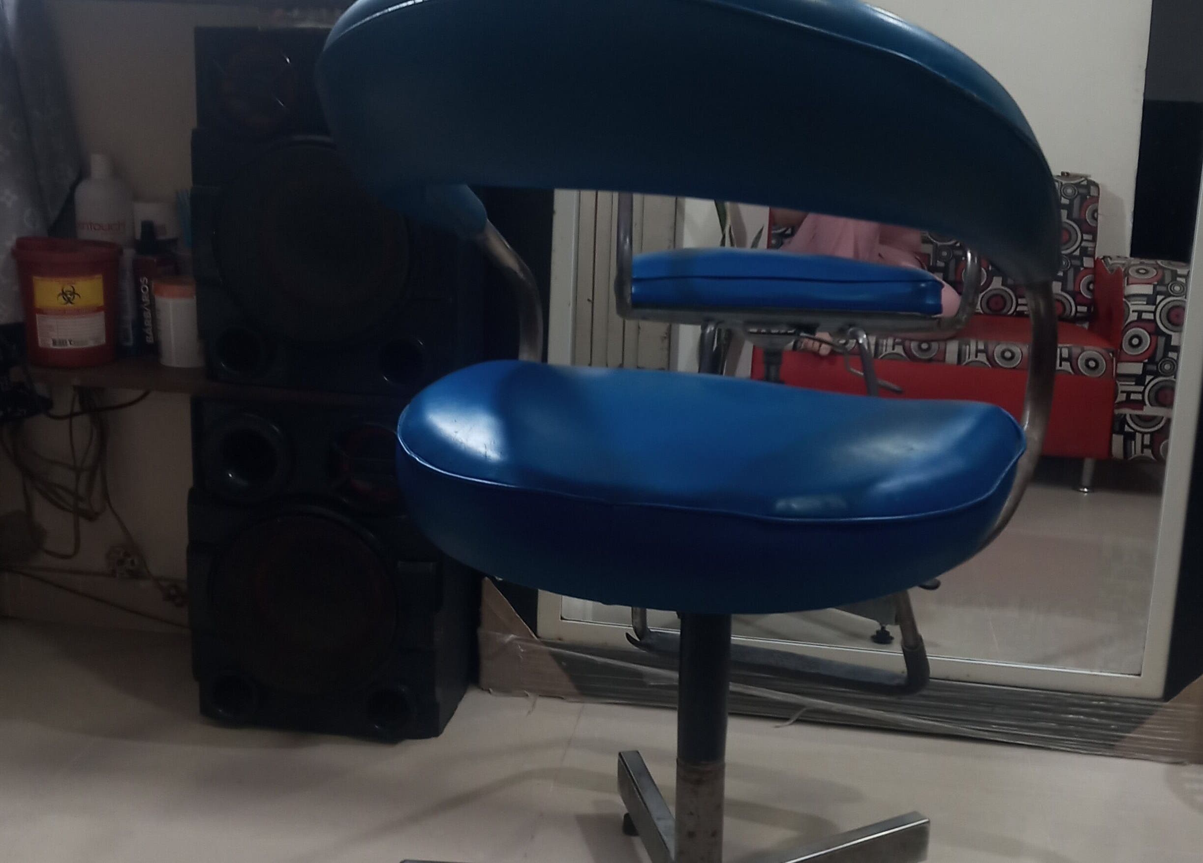 Silla de barbero azul en Barber Bombsquad, Cali, Valle Del Cauca, CO, reflejada en espejo.