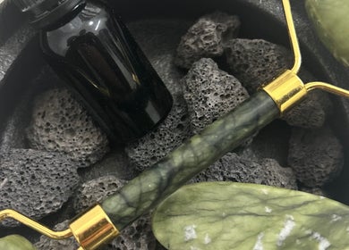 Jade roller and essential oil on black stones at Sanctuary, Louth, England, GB, promoting relaxation and rejuvenation.