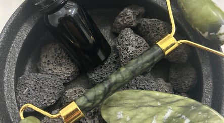 Jade roller and essential oil on black stones at Sanctuary, Louth, England, GB, promoting relaxation and rejuvenation.