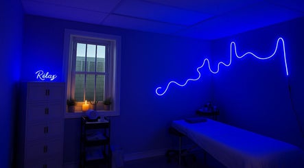Blue-lit treatment room at 416Skin Aesthetics & Academy, Toronto, Ontario, CA. Features 'Relax' neon sign.