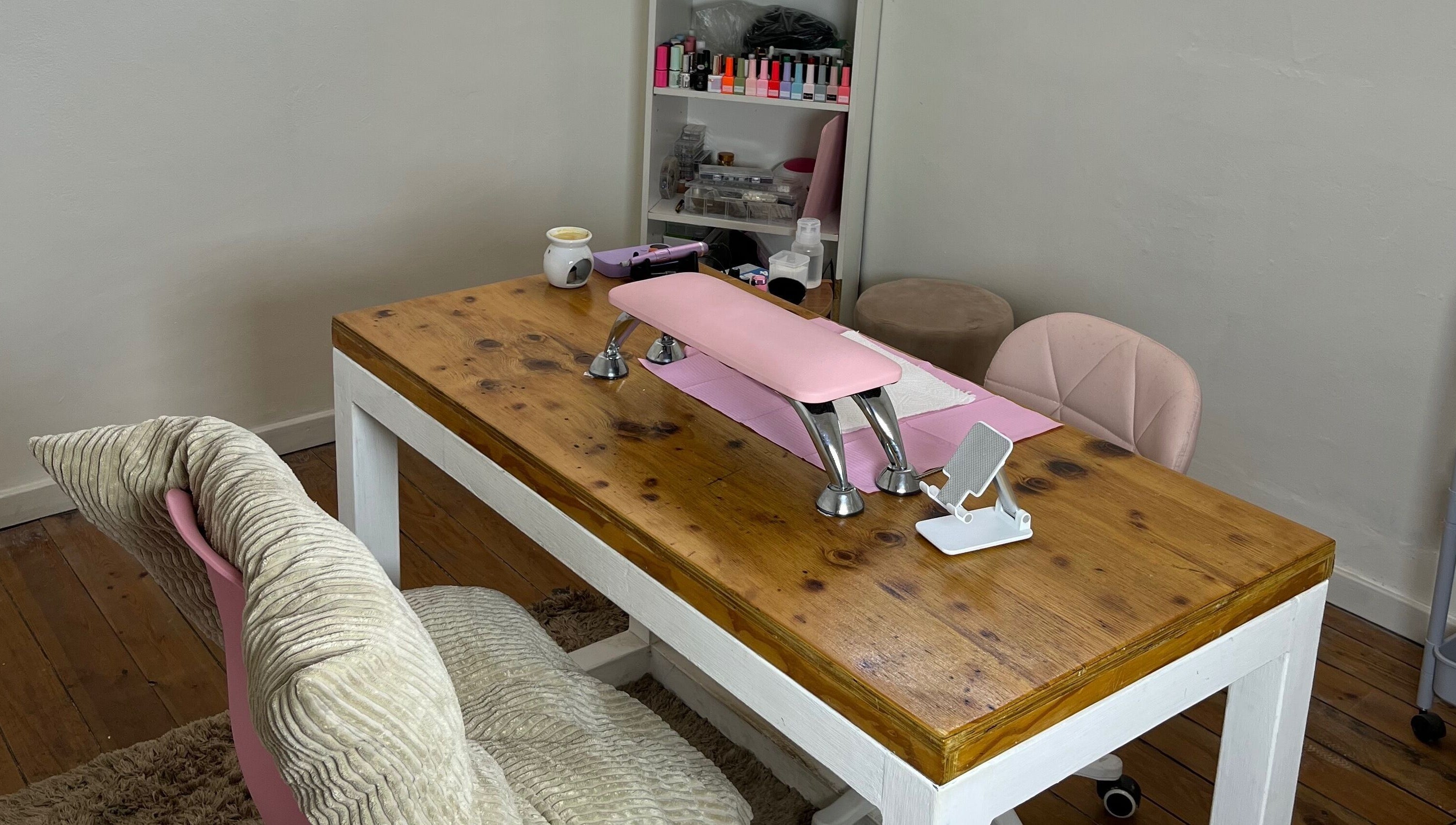 Cozy nail care area at Saintysclaws, Randburg, Gauteng, ZA, showcasing a polished wood table with pink accents.