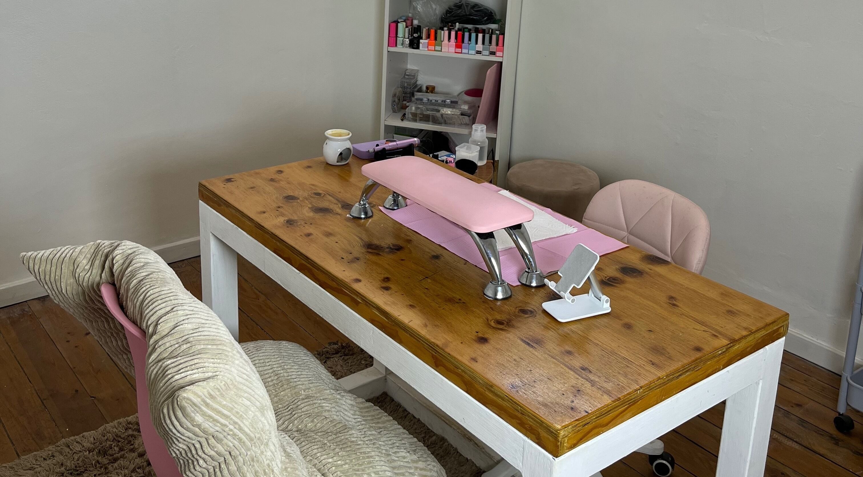 Cozy nail care area at Saintysclaws, Randburg, Gauteng, ZA, showcasing a polished wood table with pink accents.