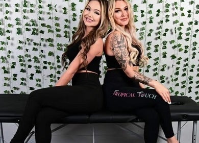 Two women in black attire at T&S Paradise Touch Spa, San Jose, California, US, seated on a massage table.