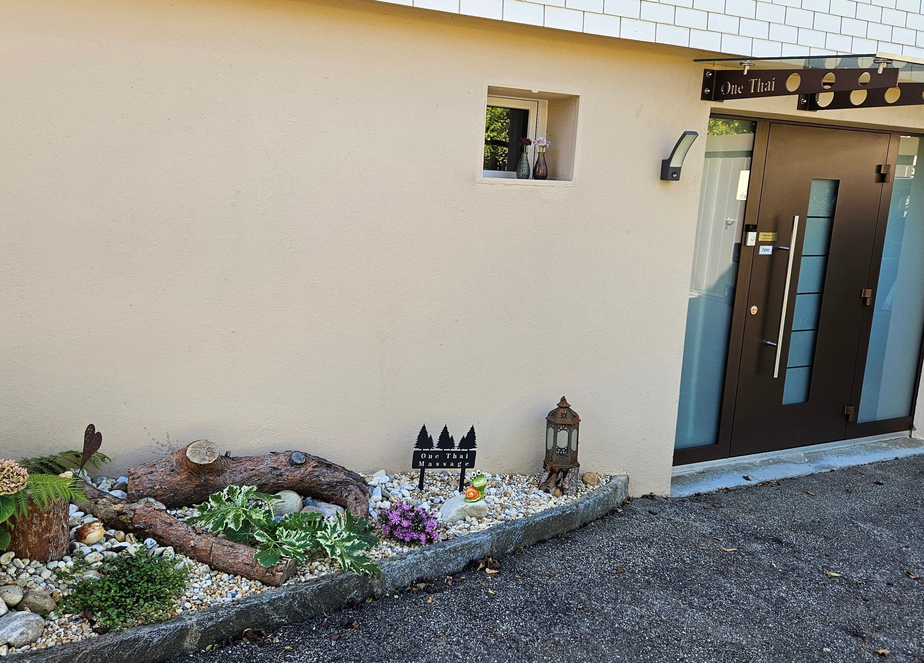Eingang von One Thai Massage Ipsach in Ipsach, Bern, CH mit dekorativem Garten.