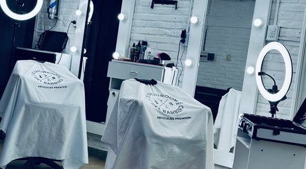 Moderno salón de Bautiibarberr en Villa Quinteros, Tucumán, AR, con espejos iluminados y sillas cubiertas.