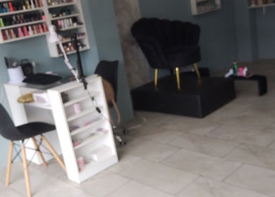 Interior de Divine Beauty Studio en Portoviejo, Manabí, EC con elegante silla y estantería de esmaltes.