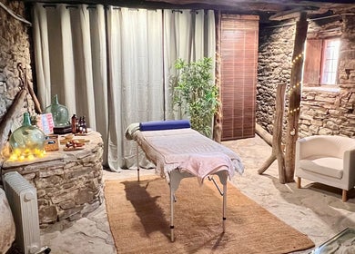 Sala de masaje en Hub de Bienestar Pirineo, Troncedo, Aragón, ES, con decoración rústica y piedra natural.