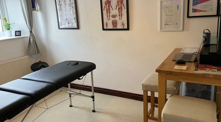 Cozy massage room at HBW Sports Massage, Lower Westford, England, GB with massage table and anatomical posters.