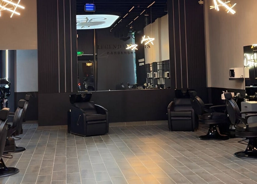 Modern interior of Legendary Cuts Barbershop in Riyadh, SA featuring sleek black chairs and elegant lighting.
