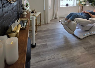 Client relaxing on a modern chair at Beauty by Bahar, Toronto, Ontario, CA, with candles and chic decor.