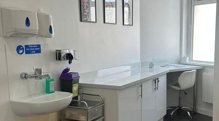 A clean, modern treatment room at Simply Glow Aesthetics, Bathgate, Scotland, GB with white cabinetry and handwash sink.