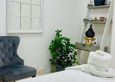 Cozy therapy room at Soi52 Thai Therapy, Leicester, England, GB, with plush chair, potted plant, and decorative shelf.