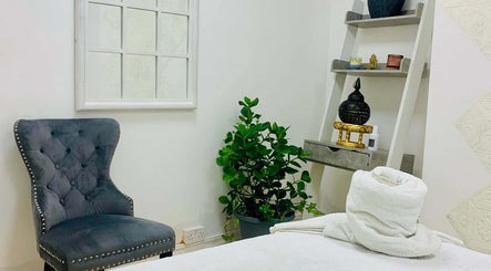 Cozy therapy room at Soi52 Thai Therapy, Leicester, England, GB, with plush chair, potted plant, and decorative shelf.