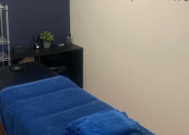 Relaxing massage room at SM Sports Therapy, Warrington, England, GB with a blue-covered therapy bed.