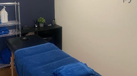 Relaxing massage room at SM Sports Therapy, Warrington, England, GB with a blue-covered therapy bed.