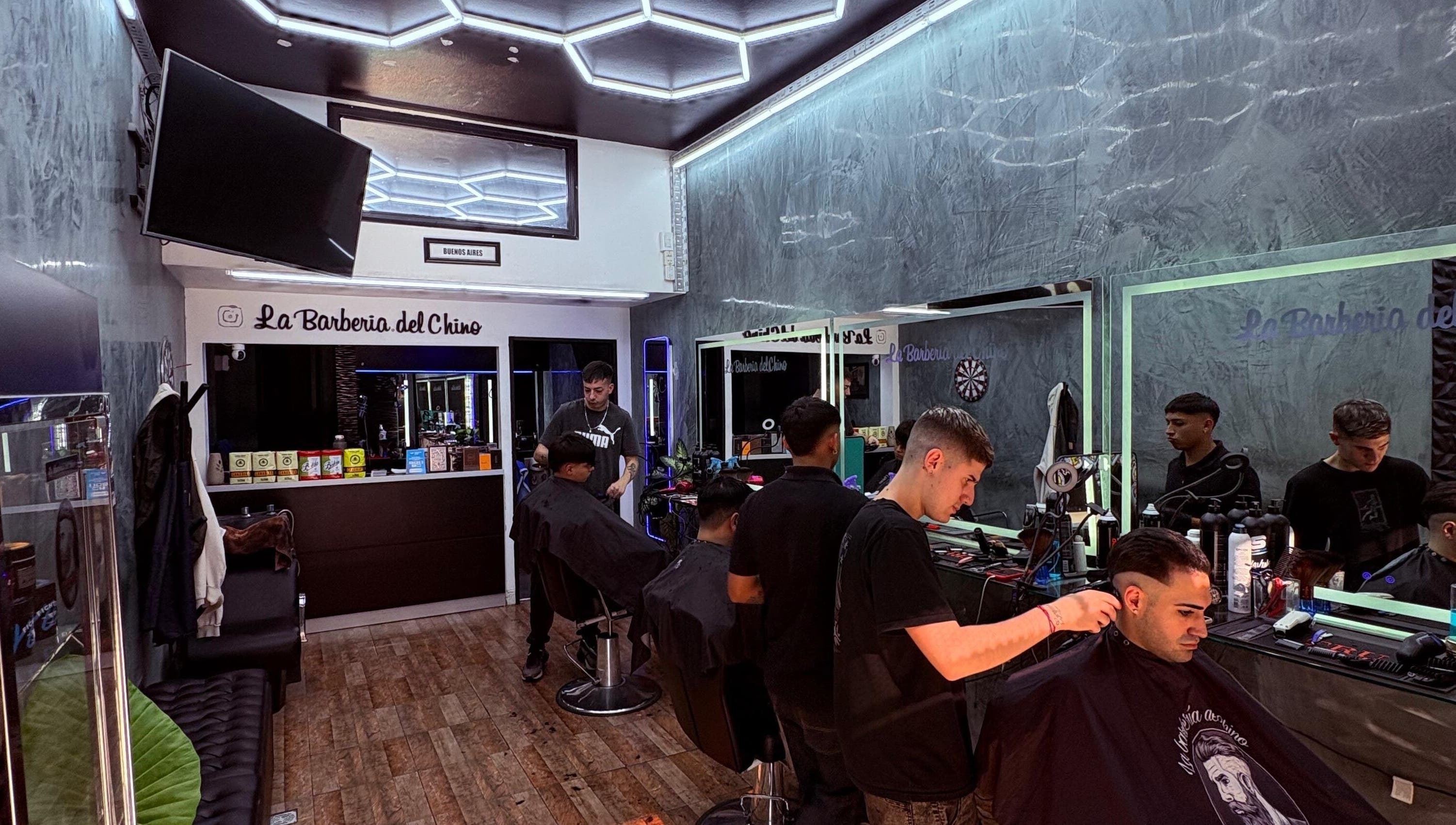 Interior de La Barbería Del Chino en Buenos Aires con barberos trabajando en clientes.