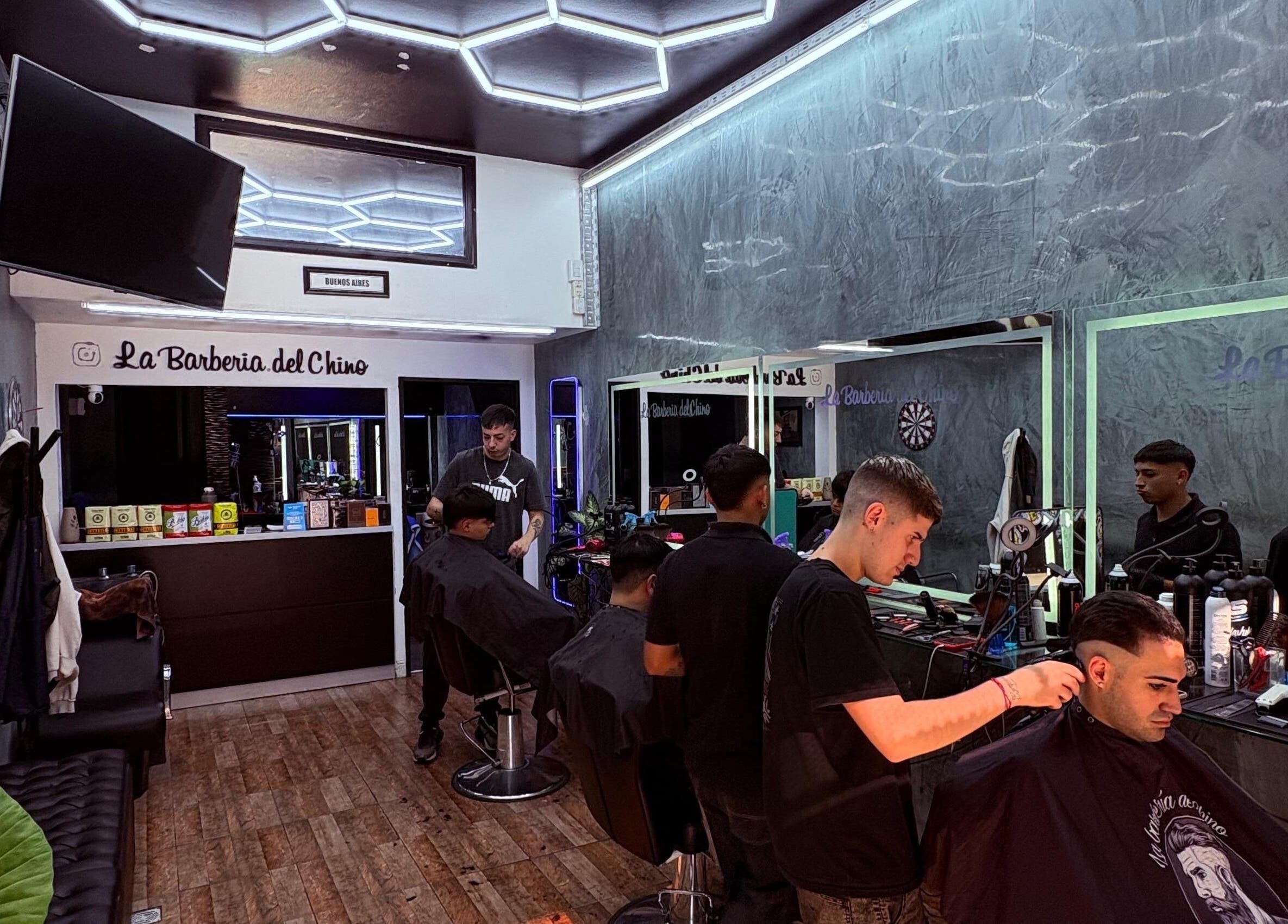 Interior de La Barbería Del Chino en Buenos Aires con barberos trabajando en clientes.