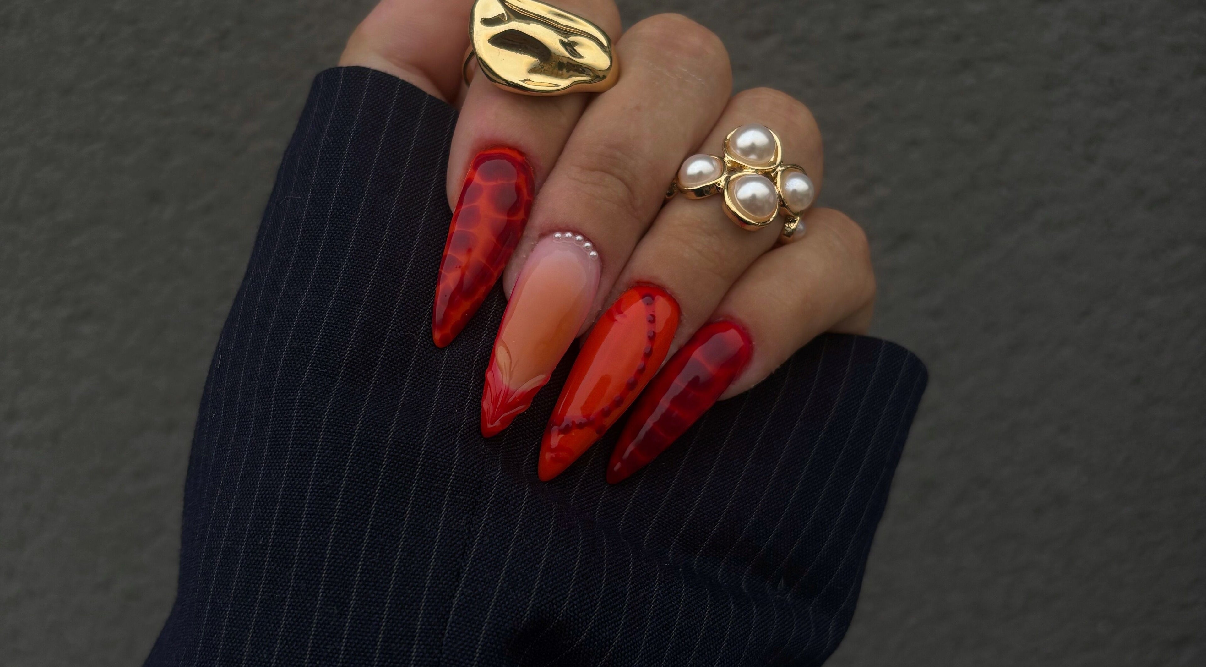 Ongles rouge élégant chez Hnails, Albert, Hauts-de-France, FR, avec motifs artistiques et bagues dorées.