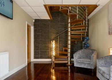 Elegant spiral staircase in Elite Medical, Sports Therapy and Ear Care, Shaw, England with cozy gray chairs.