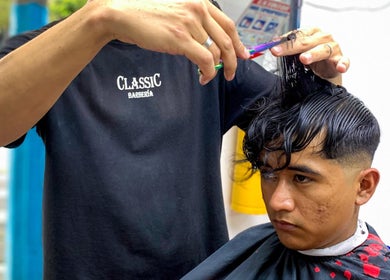 Barbero de Classic Barbería, Medellín, Antioquia, CO, realizando un corte de cabello preciso.