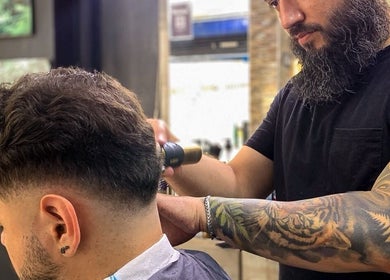 Barbero tatuado estilizando cabello en Classic Barbería, Medellín, Antioquia, CO.