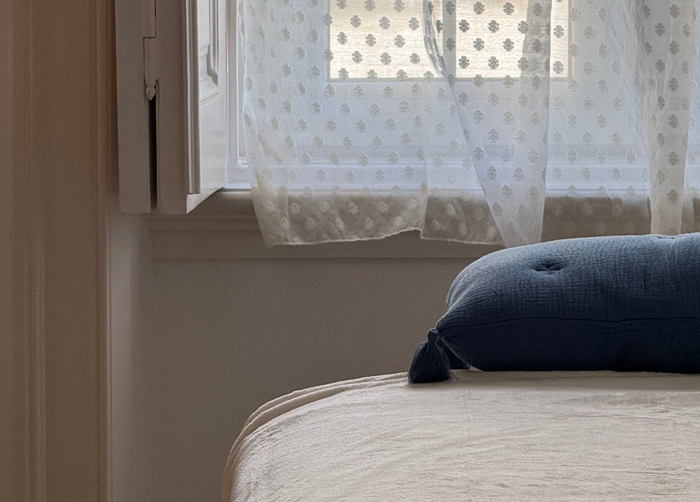 Cozy room at Lymph by Camila in Lisbon, Lisbon, PT, featuring a cushioned bed by a sunlit window with curtains.