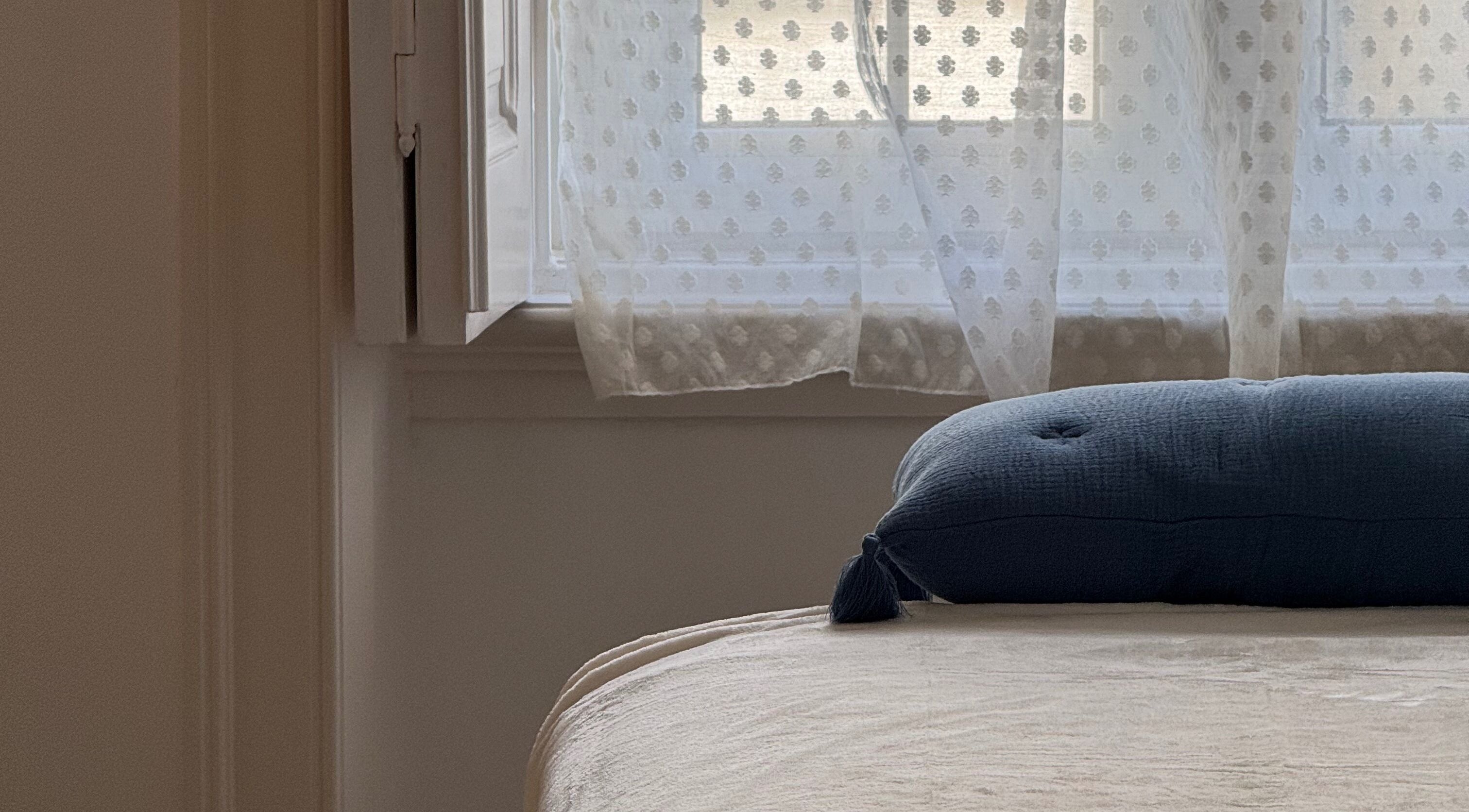 Cozy room at Lymph by Camila in Lisbon, Lisbon, PT, featuring a cushioned bed by a sunlit window with curtains.
