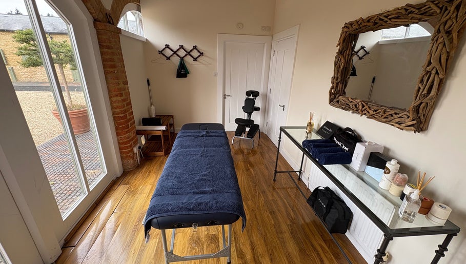 Relaxing treatment room at SRSportsRehab, Silverstone, England, GB featuring massage table and natural decor.