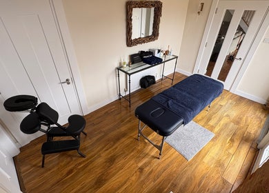 Relaxing therapy room at SRSportsRehab, Silverstone. Wood flooring, massage table, and therapy chair for wellness.
