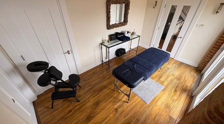 Relaxing therapy room at SRSportsRehab, Silverstone. Wood flooring, massage table, and therapy chair for wellness.