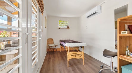 Lichte massageruimte bij Voetreflextherapie Bonaire in Nikiboko met massagetafel en houten meubels.