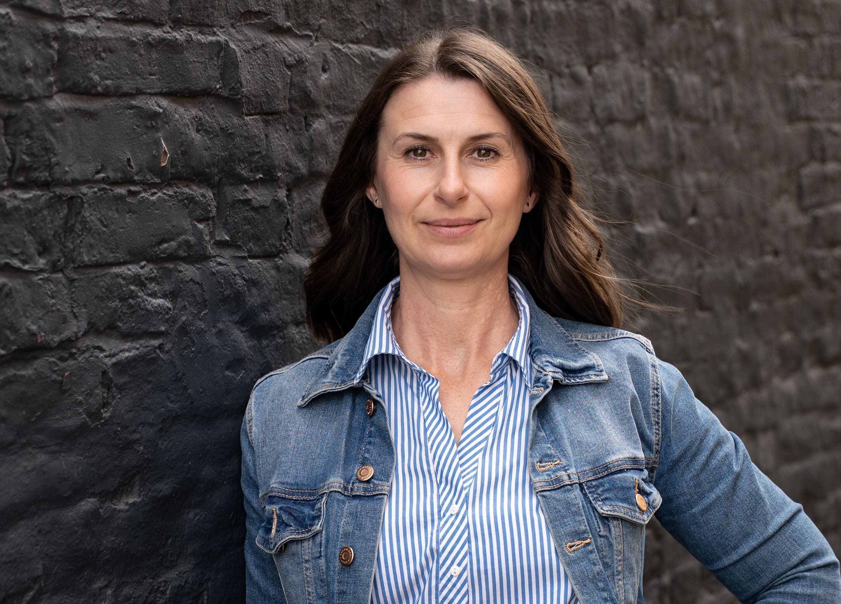 Woman in denim jacket by brick wall at Lindsey Graham Physio & Holistics, Chester-le-street, England, GB.
