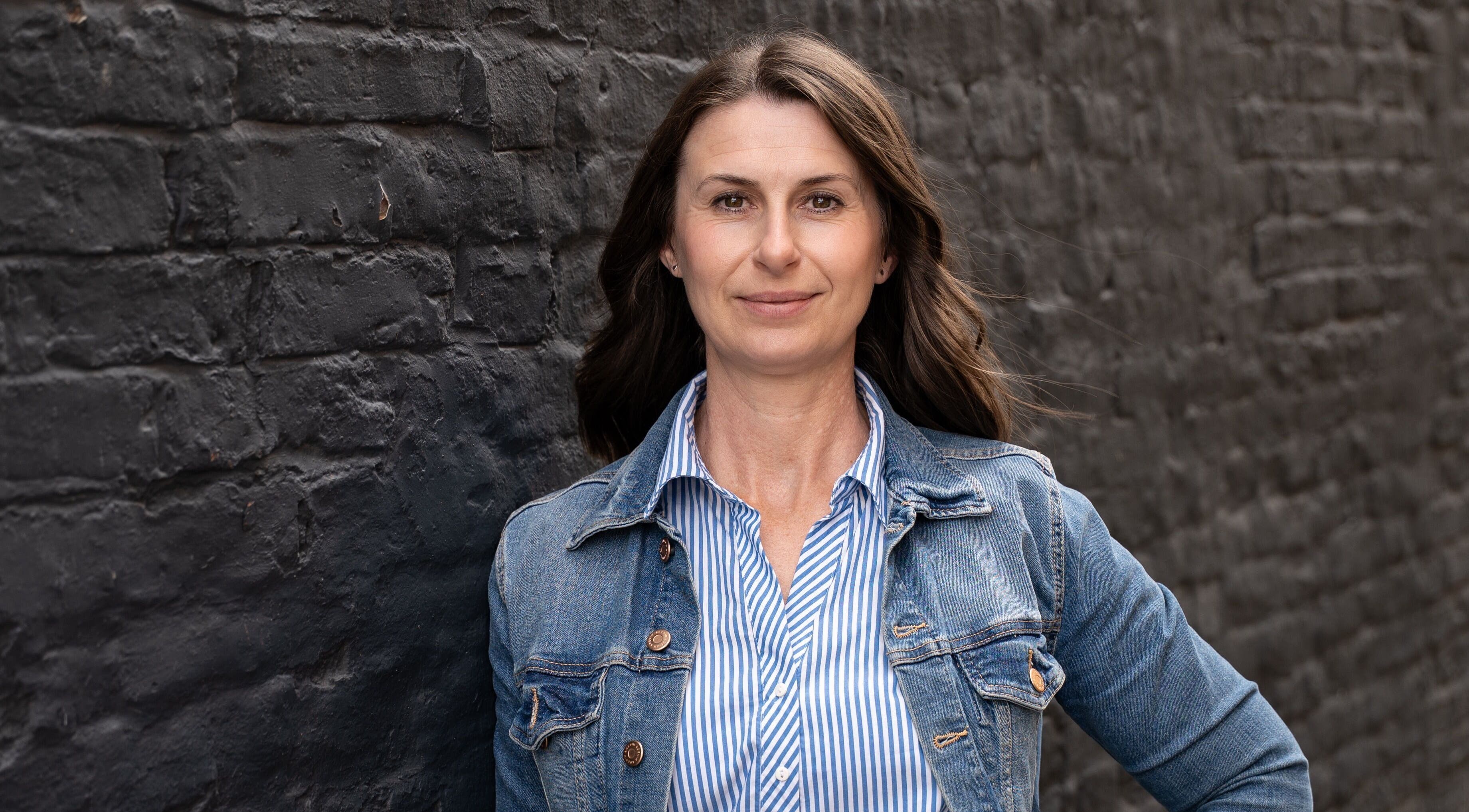 Woman in denim jacket by brick wall at Lindsey Graham Physio & Holistics, Chester-le-street, England, GB.