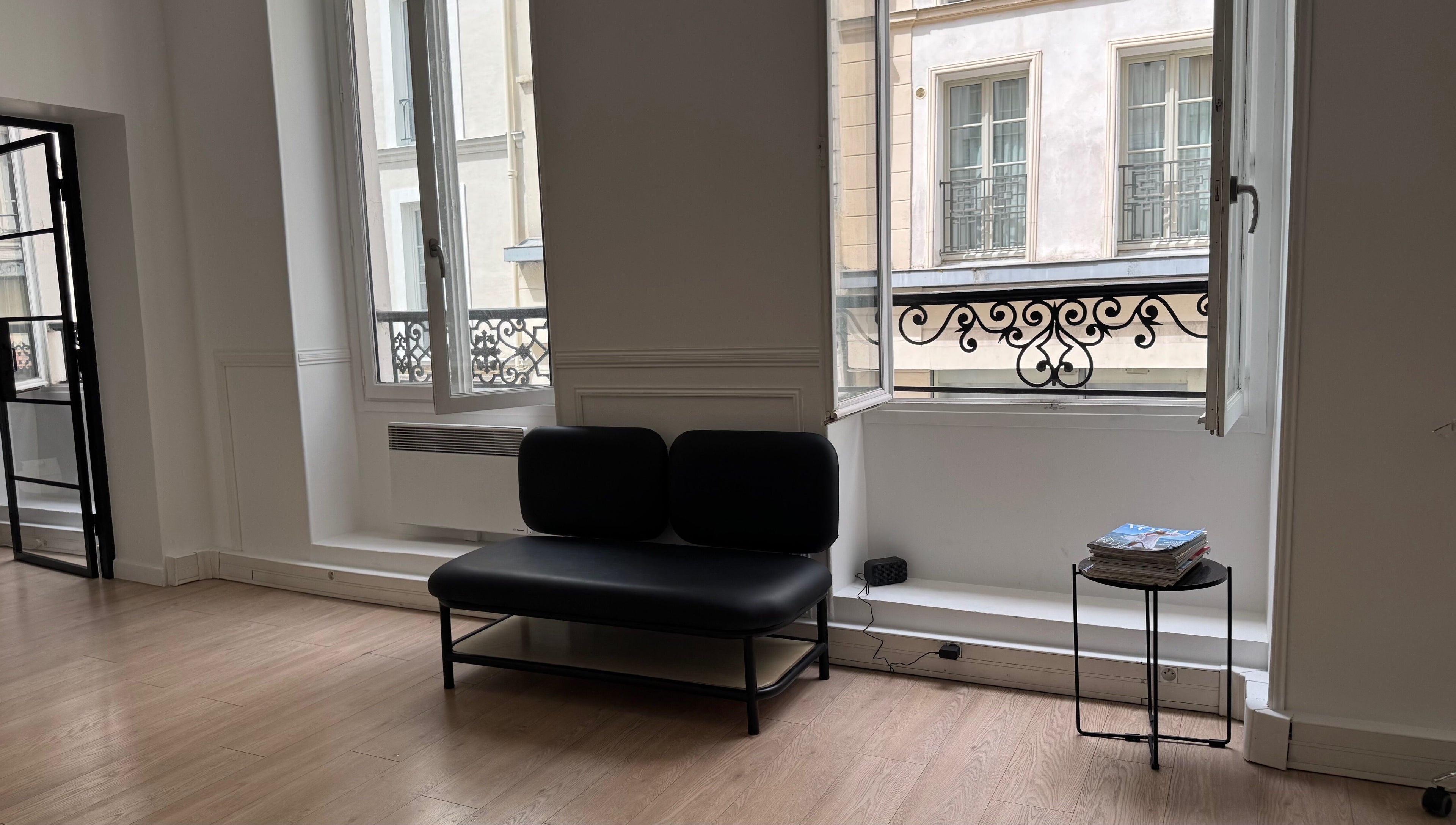 Intérieur moderne de Leonard à Paris, Île-de-France, FR avec canapé noir et fenêtres lumineuses.