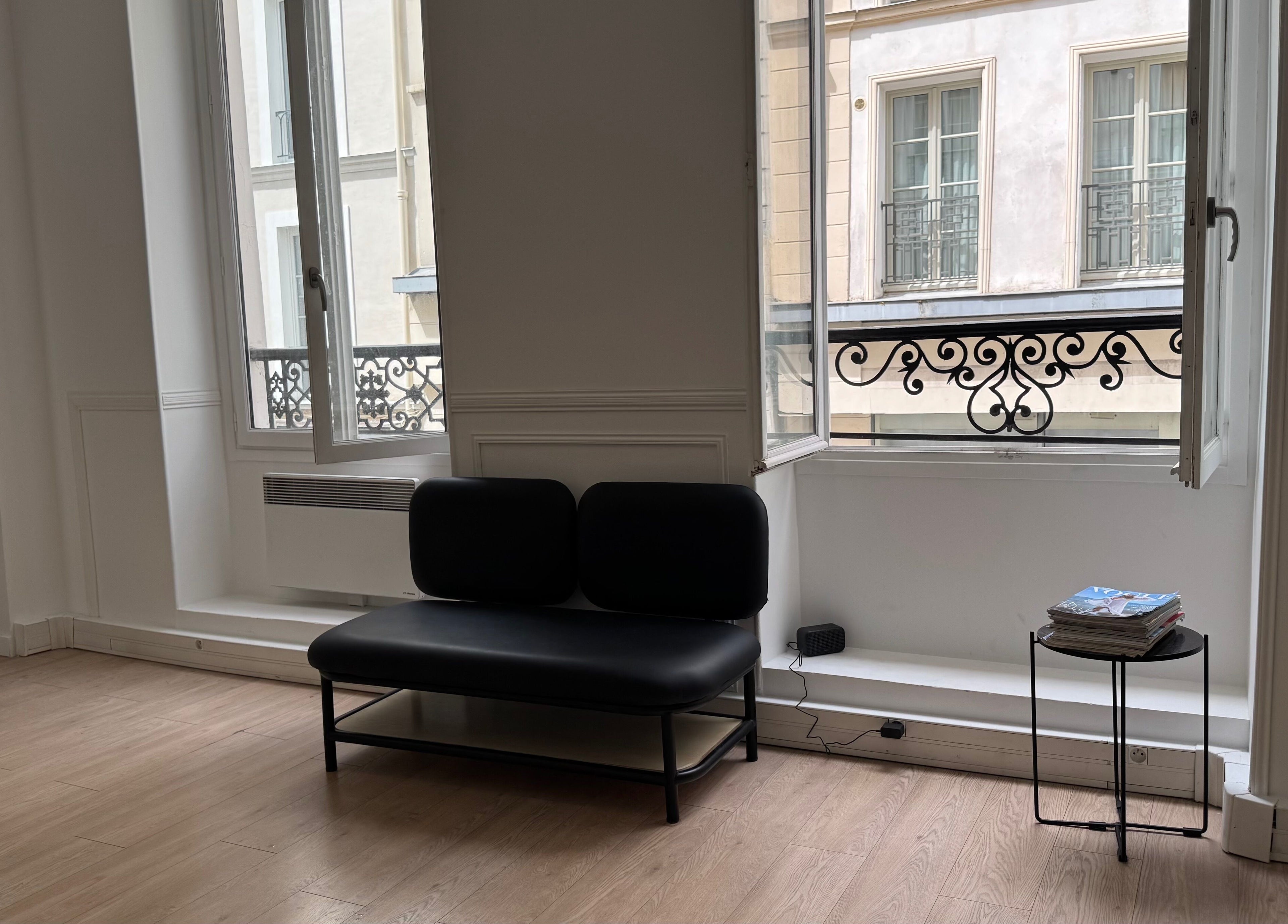 Intérieur moderne de Leonard à Paris, Île-de-France, FR avec canapé noir et fenêtres lumineuses.