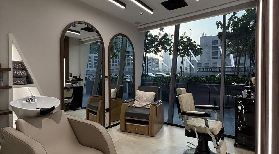 Modern interior of Hamza Abdulal Men Salon in Dubai, Dubai, AE, featuring stylish chairs and large mirrors.