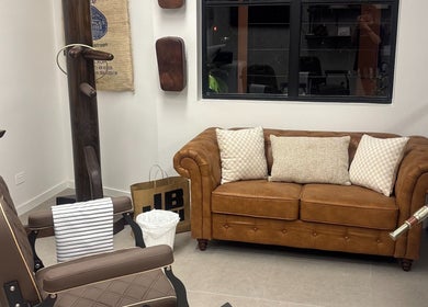 Inviting barber waiting area at Piccante Barbers, Peregian Springs, Queensland, AU with leather sofa and decor.