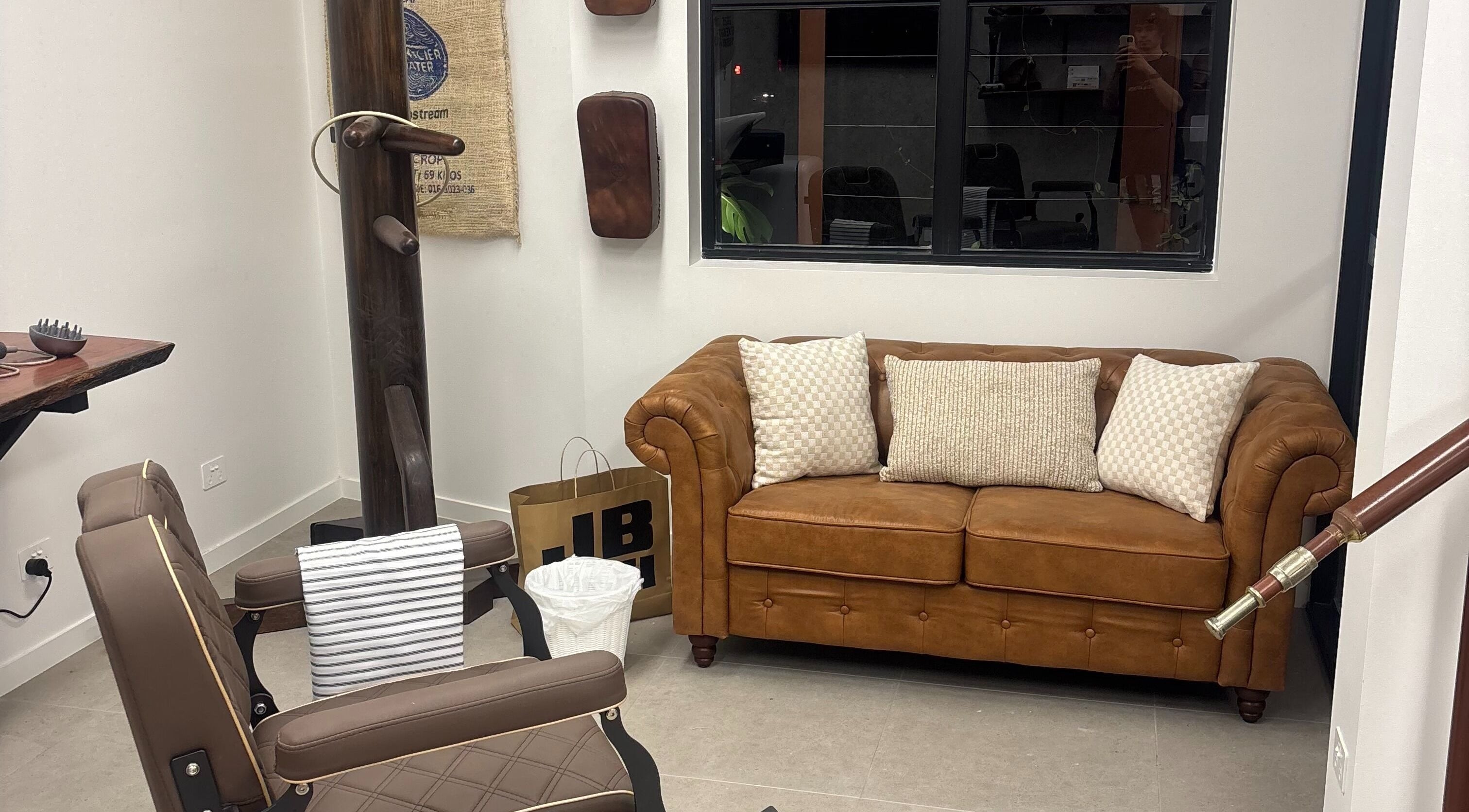 Comfortable waiting area at Piccante Barbers, Peregian Springs, Queensland, AU with a plush leather sofa.