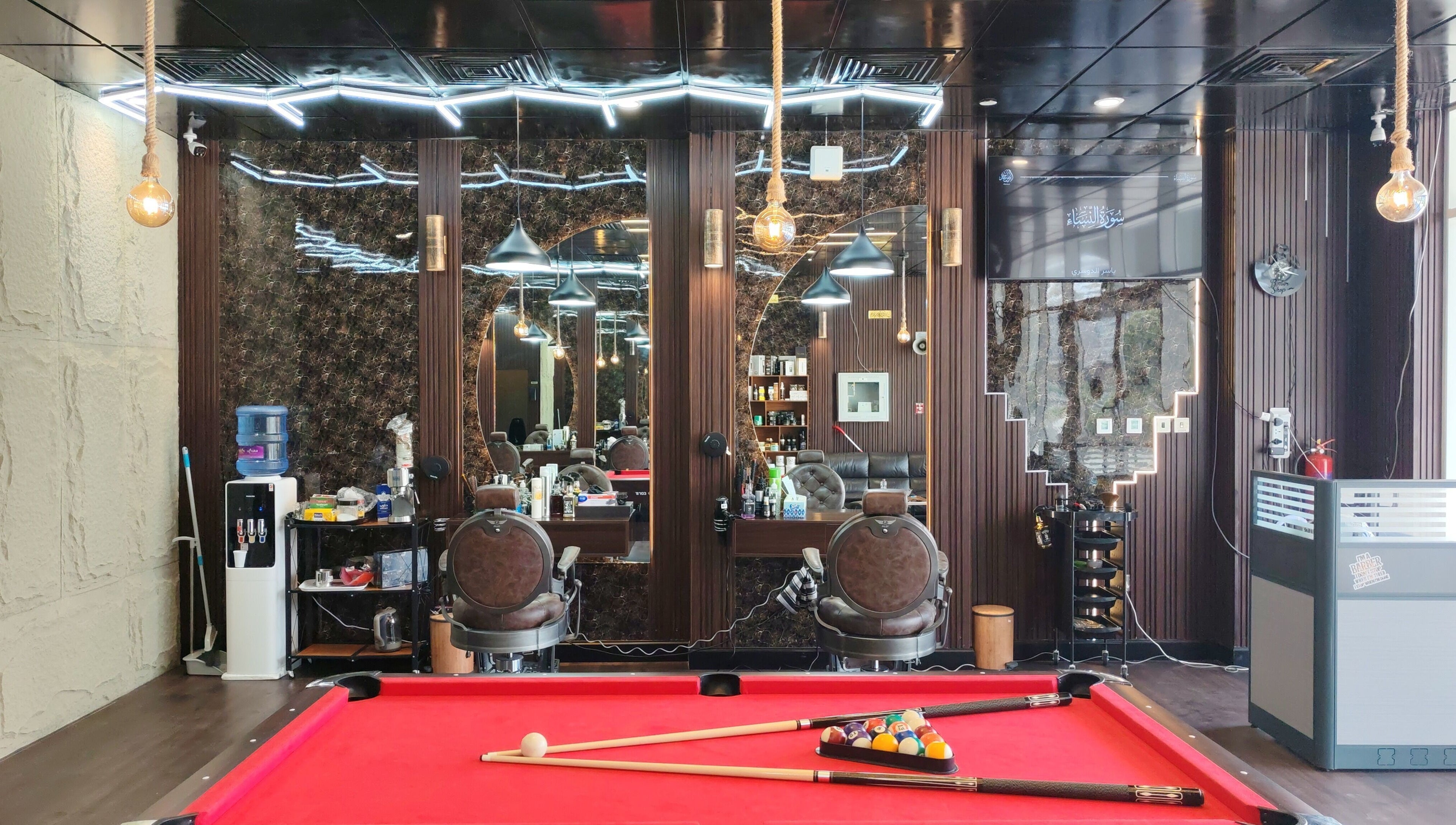 داخل صالون Les Messieurs في أبو ظبي، يجمع بين الرفاهية والأناقة بجوار طاولة بلياردو.