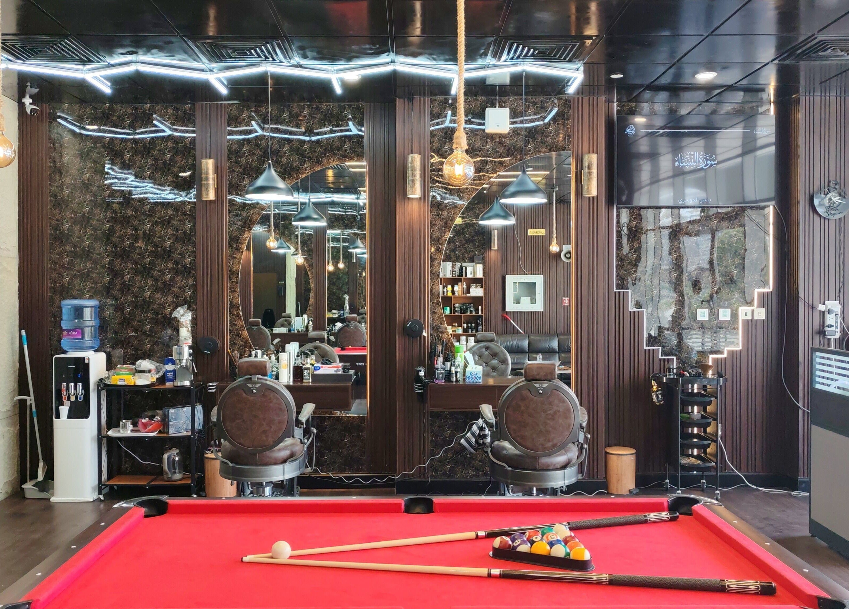 داخل صالون Les Messieurs في أبو ظبي، يجمع بين الرفاهية والأناقة بجوار طاولة بلياردو.