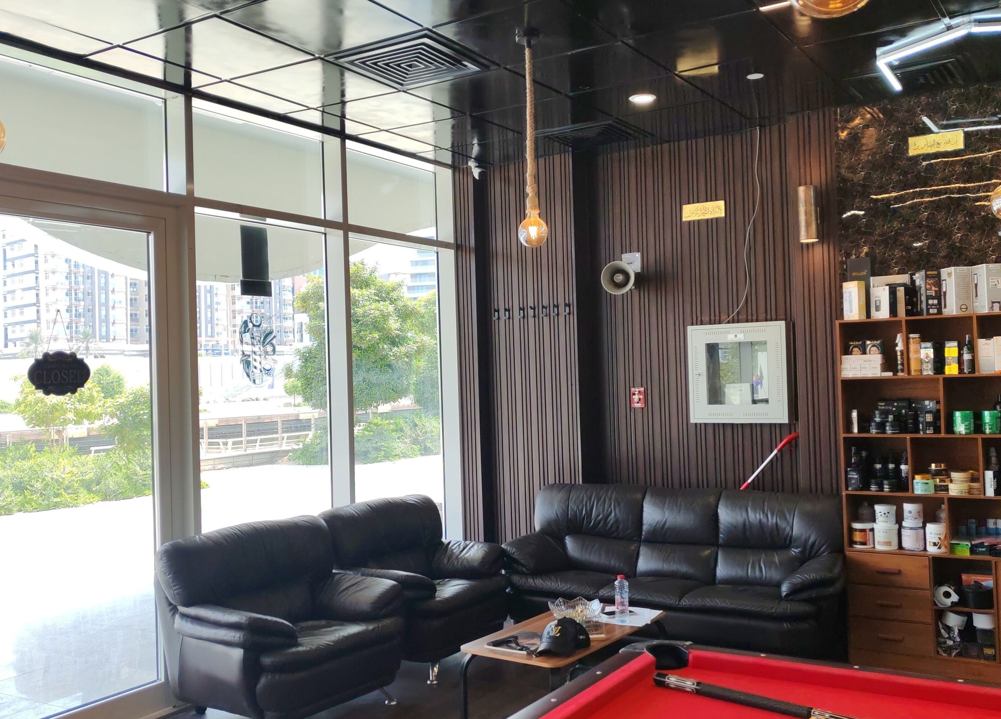 منطقة جلوس مريحة في Les Messieurs Salon, أبو ظبي, أبو ظبي, AE بأثاث فاخر وخزانة منتجات.