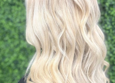 Blonde wavy hair styled at The Dolls Lounge, Leeds, England, GB, with a lush green backdrop.