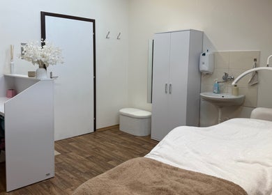 Moderní beauty místnost v SkinMax, Středočeský Kraj, CZ s masážním lehátkem a elegantní výzdobou.