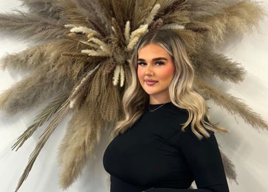 A stylish woman at Studio S By Sienna in Stoke-on-Trent, England, GB, standing against a decorative pampas grass display.