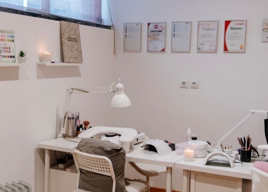 Mesa de manicure no DN Beauty Space em Mafra, Lisboa, PT, com decoração minimalista e certificados na parede.