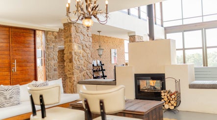 Charming lounge with rustic stone and fireplace at Vygenhoek Spa & Farmhouse in Dullstroom, Mpumalanga, ZA.