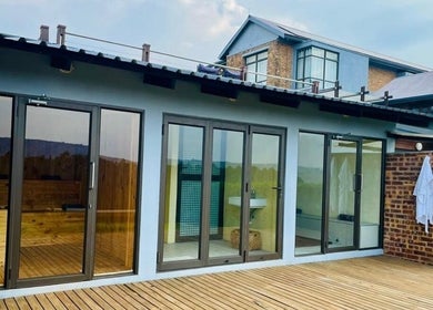 Vygenhoek Spa & Farmhouse's serene deck in Dullstroom, Mpumalanga, ZA, with robes and glass doors.