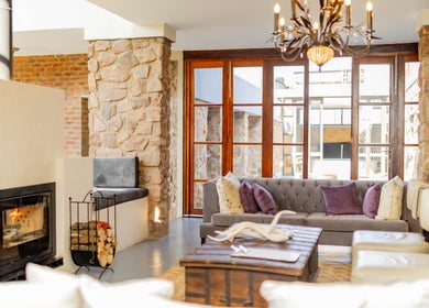 Charming lounge at Vygenhoek Spa & Farmhouse, Dullstroom, Mpumalanga, ZA with plush seating and stone walls.