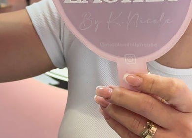 Woman holding a pink mirror showcasing freshly manicured nails at Nicole’s Dolls House, London, England, GB.
